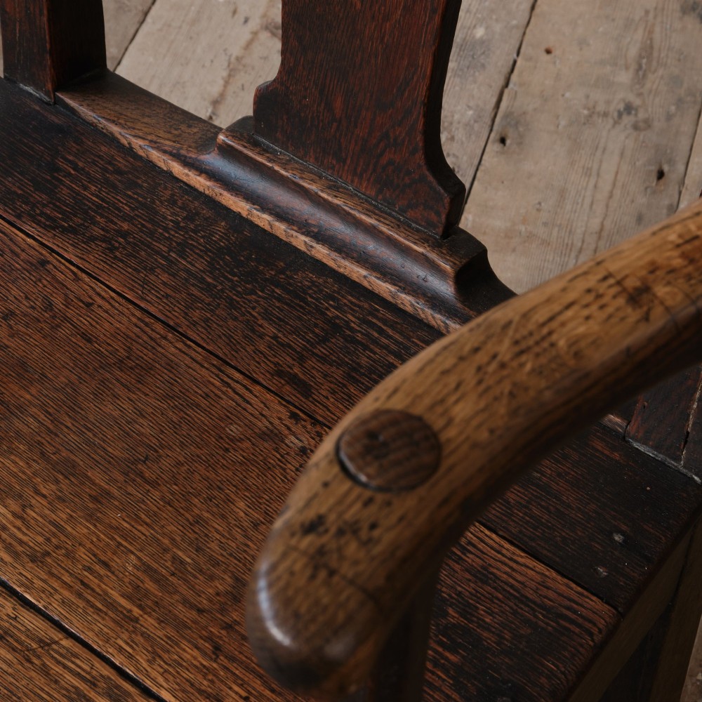 A Georgian oak open armchair featuring a vase-shaped splat back, solid seat, shaped armrests, and an H-stretcher base. View VI