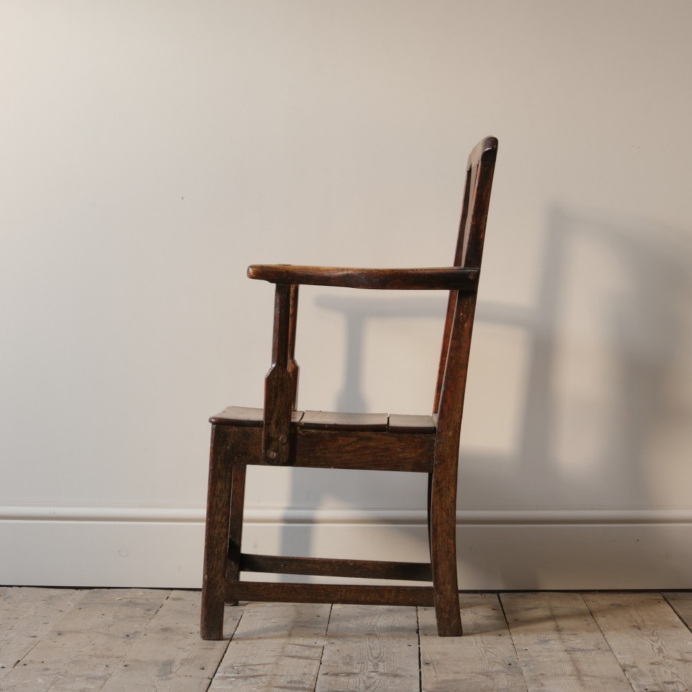 A Georgian oak open armchair featuring a vase-shaped splat back, solid seat, shaped armrests, and an H-stretcher base. View VII