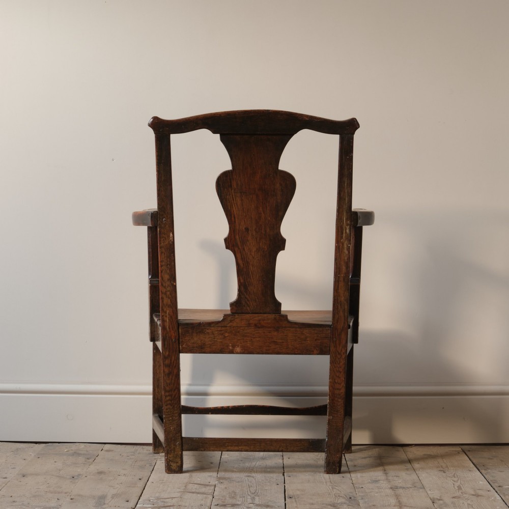 A Georgian oak open armchair featuring a vase-shaped splat back, solid seat, shaped armrests, and an H-stretcher base. View IX