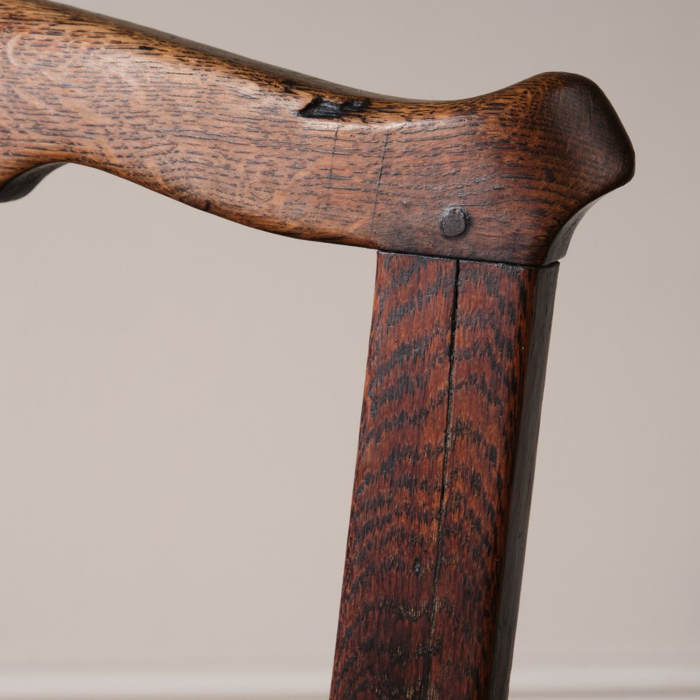 A Georgian oak open armchair featuring a vase-shaped splat back, solid seat, shaped armrests, and an H-stretcher base. View X