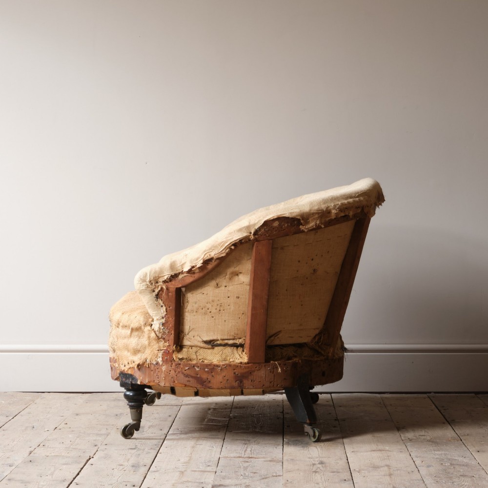 Mid-19th century Victorian Howard & Sons curved-back sofa stripped to its calico and hessian under-upholstery with turned front legs on brass castors. View IV