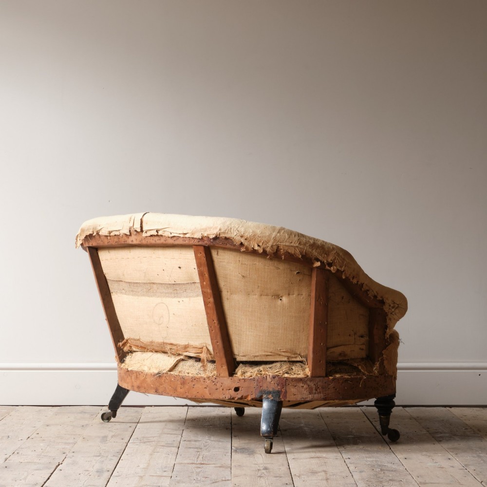 Mid-19th century Victorian Howard & Sons curved-back sofa stripped to its calico and hessian under-upholstery with turned front legs on brass castors. View VII