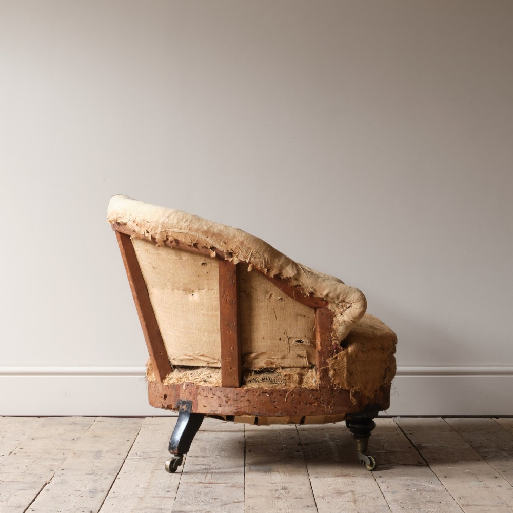 Mid-19th century Victorian Howard & Sons curved-back sofa stripped to its calico and hessian under-upholstery with turned front legs on brass castors. View VIII