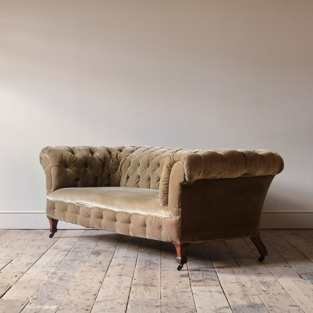 A Victorian Chesterfield sofa upholstered in deep-buttoned olive green velvet with rolled arms and turned legs on castors. View III