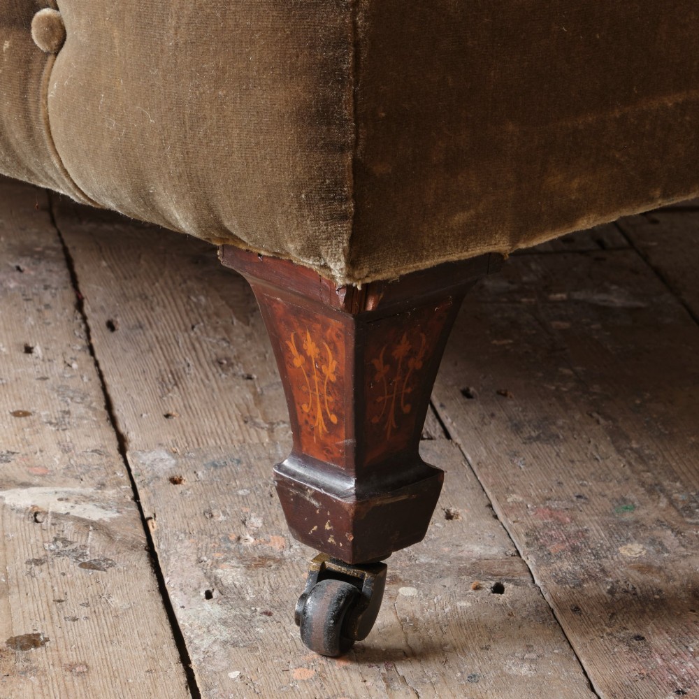 A Victorian Chesterfield sofa upholstered in deep-buttoned olive green velvet with rolled arms and turned legs on castors. View VI