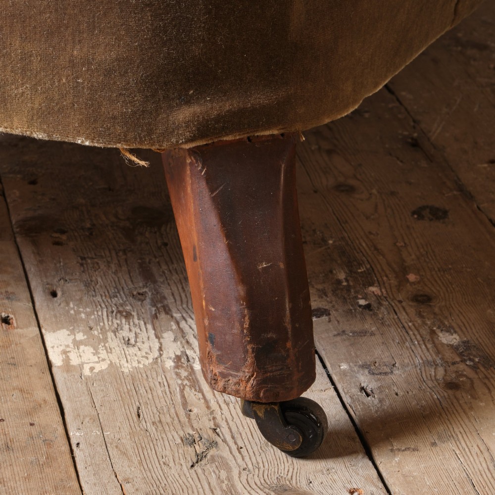 A Victorian Chesterfield sofa upholstered in deep-buttoned olive green velvet with rolled arms and turned legs on castors. View VII