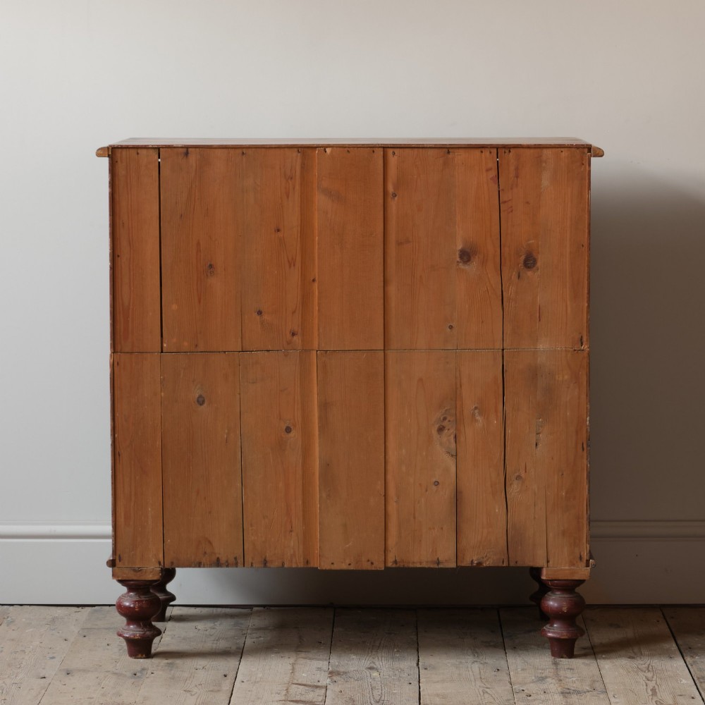 A 19th-century red painted pine chest of three drawers with wooden knob handles and turned feet. View IV
