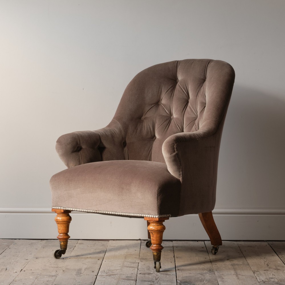 A mid-19th-century button-backed armchair upholstered in taupe velvet with turned timber front legs resting on brass castors. View II