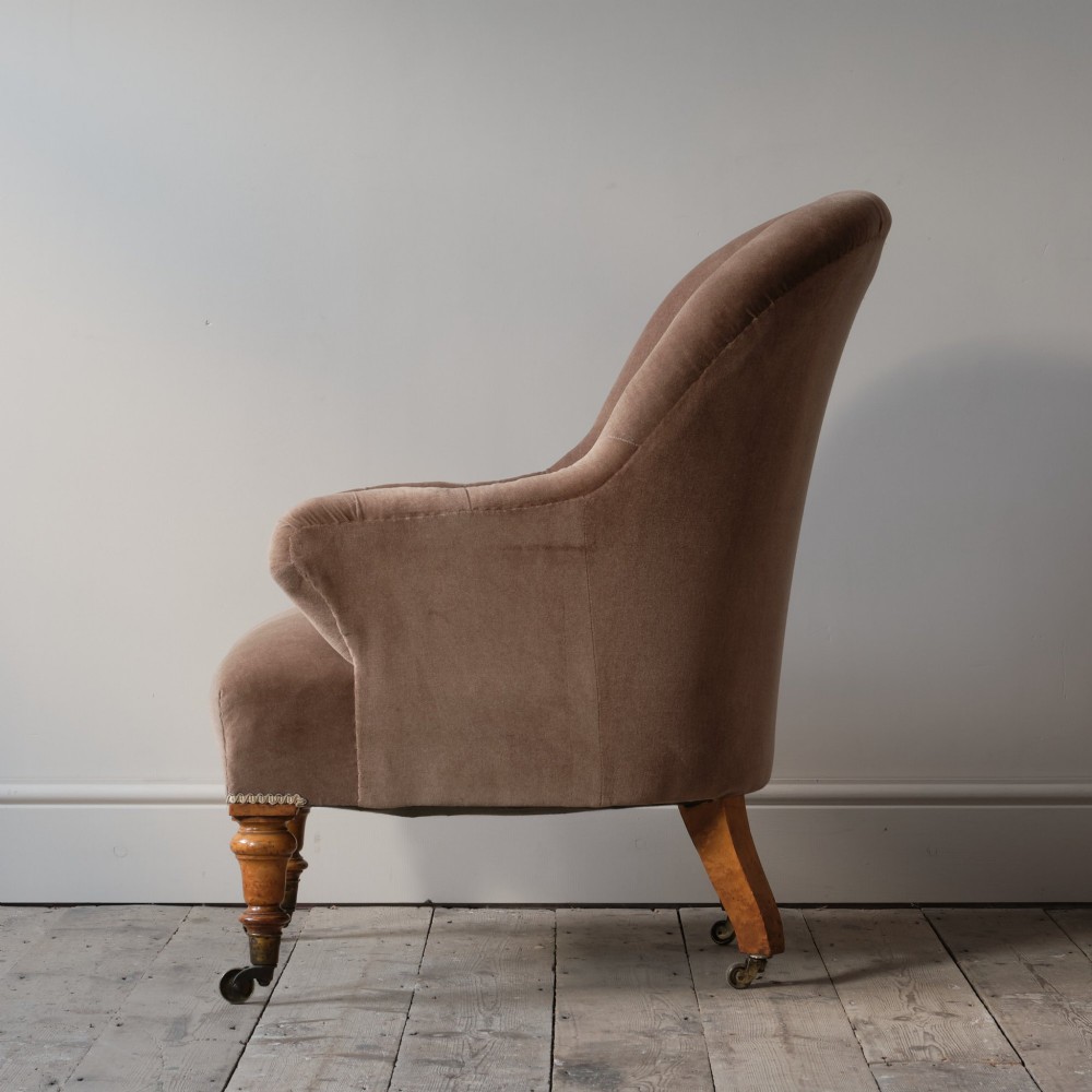 A mid-19th-century button-backed armchair upholstered in taupe velvet with turned timber front legs resting on brass castors. View IV