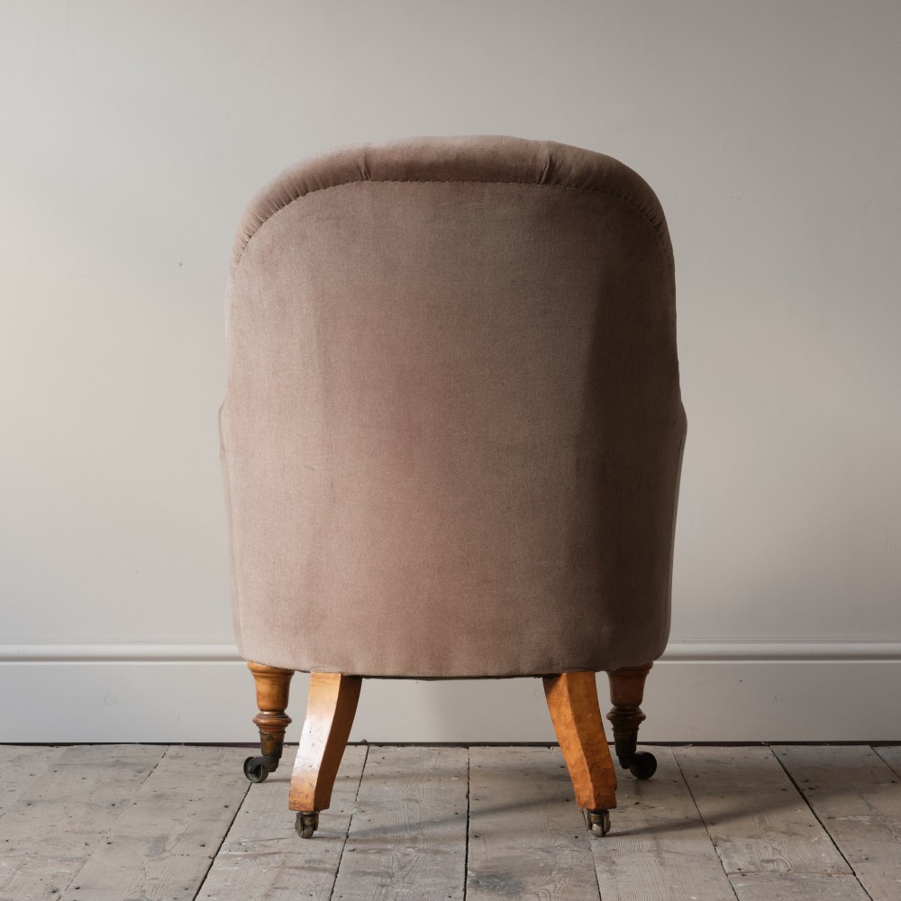 A mid-19th-century button-backed armchair upholstered in taupe velvet with turned timber front legs resting on brass castors. View VI