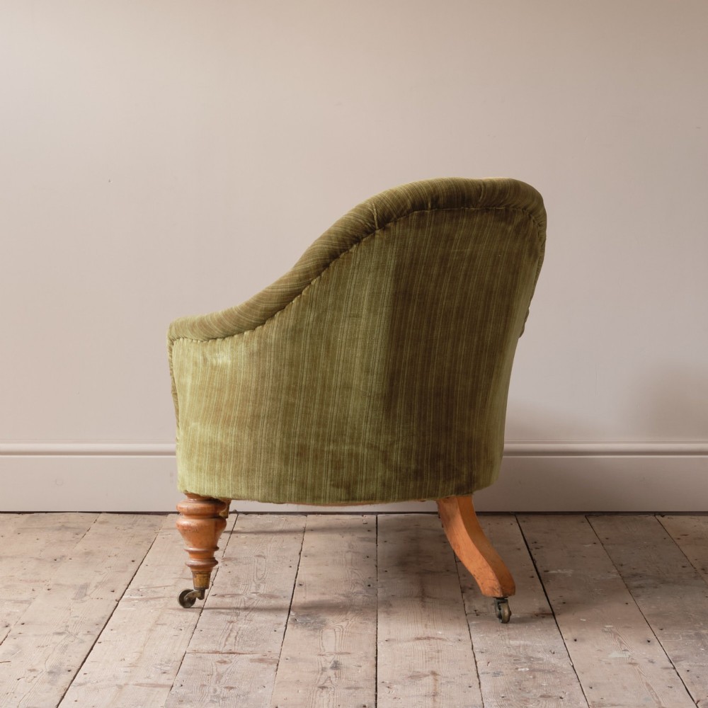 An Early Victorian chaise longue upholstered in olive green velvet with a button-backed finish, supported by turned wooden legs on brass castors. View IX