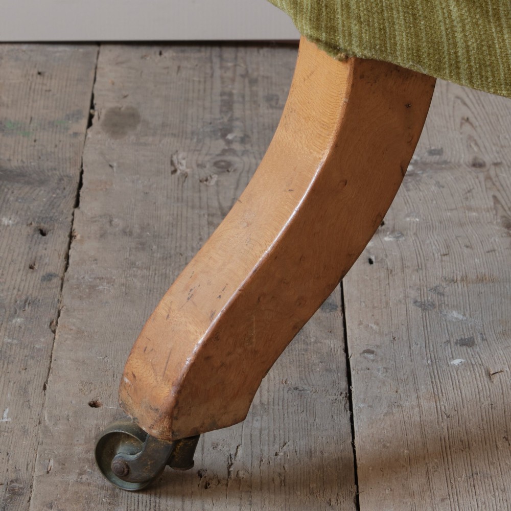An Early Victorian chaise longue upholstered in olive green velvet with a button-backed finish, supported by turned wooden legs on brass castors. View XIII