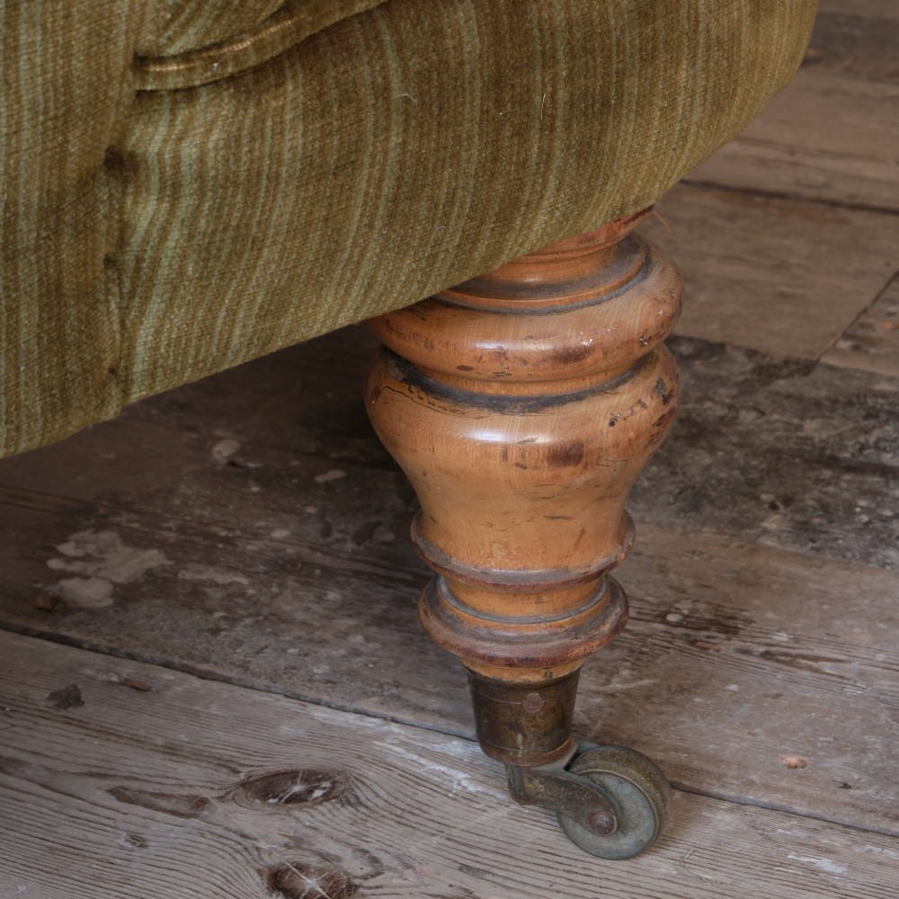 An Early Victorian chaise longue upholstered in olive green velvet with a button-backed finish, supported by turned wooden legs on brass castors. View XIV