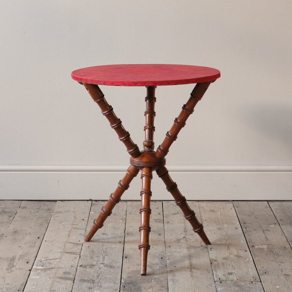 A Victorian faux bamboo walnut gypsy table featuring a circular red fabric-covered top secured with studs and supported by turned tripod legs. View II
