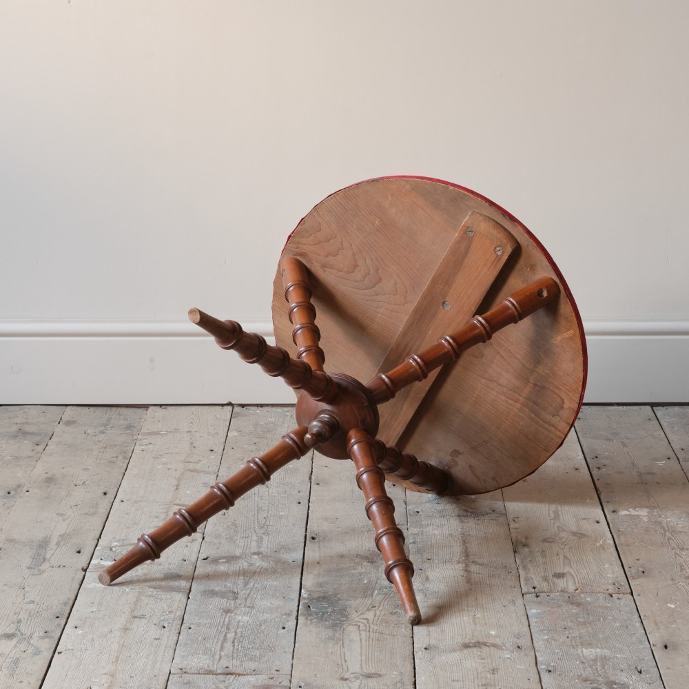 A Victorian faux bamboo walnut gypsy table featuring a circular red fabric-covered top secured with studs and supported by turned tripod legs. View V