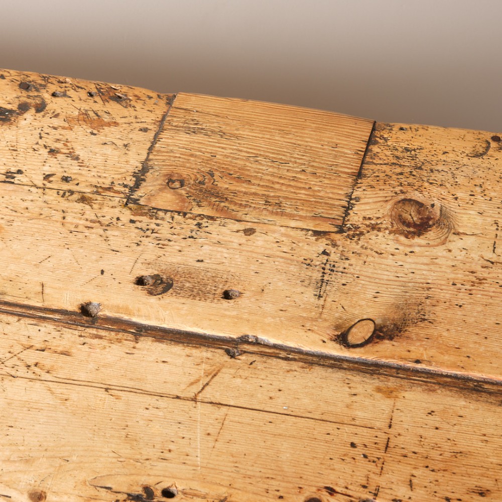 A long antique pine workbench table featuring a heavy plank top supported by a sturdy timber frame with X-frame cross bracing. View VII
