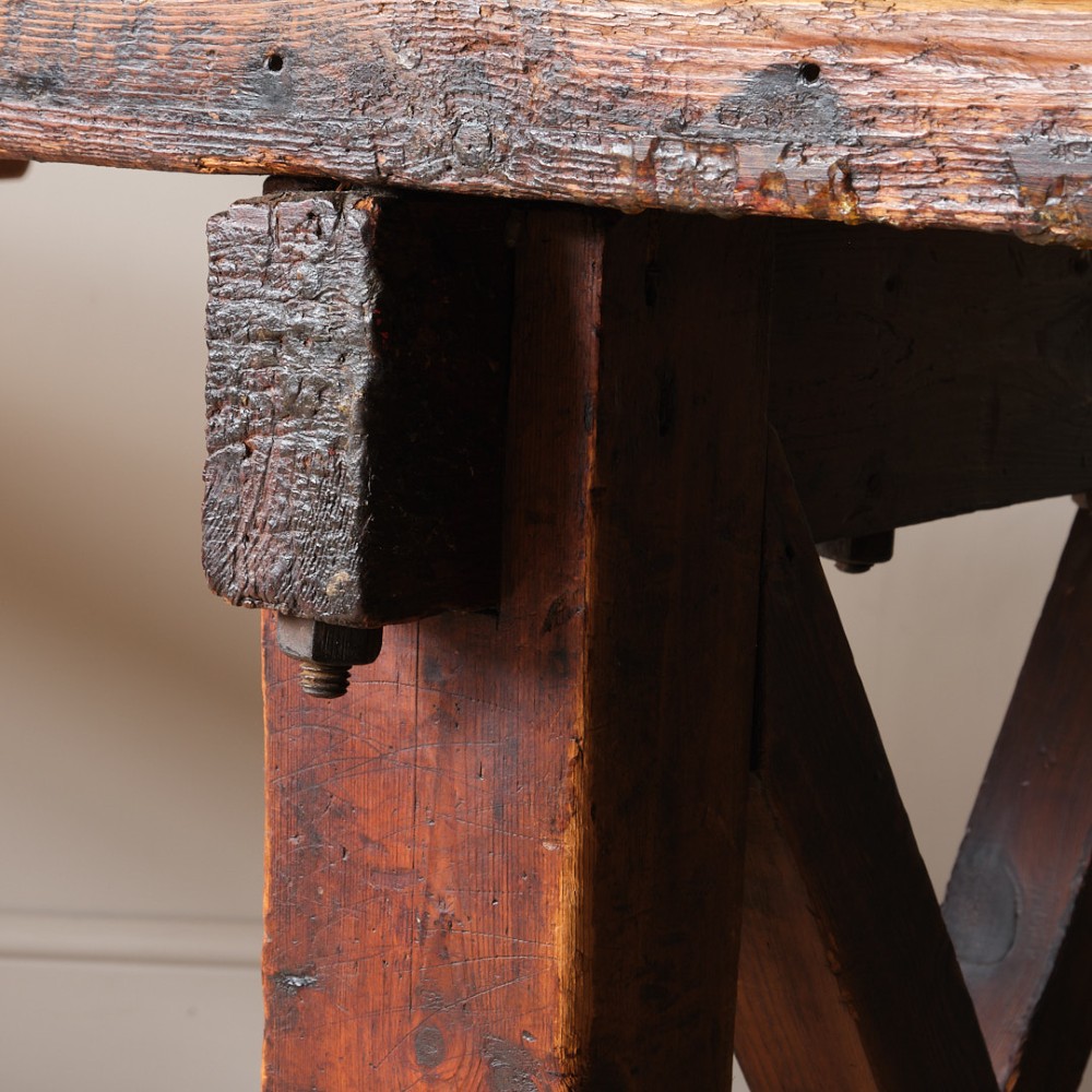 A long antique pine workbench table featuring a heavy plank top supported by a sturdy timber frame with X-frame cross bracing. View XI