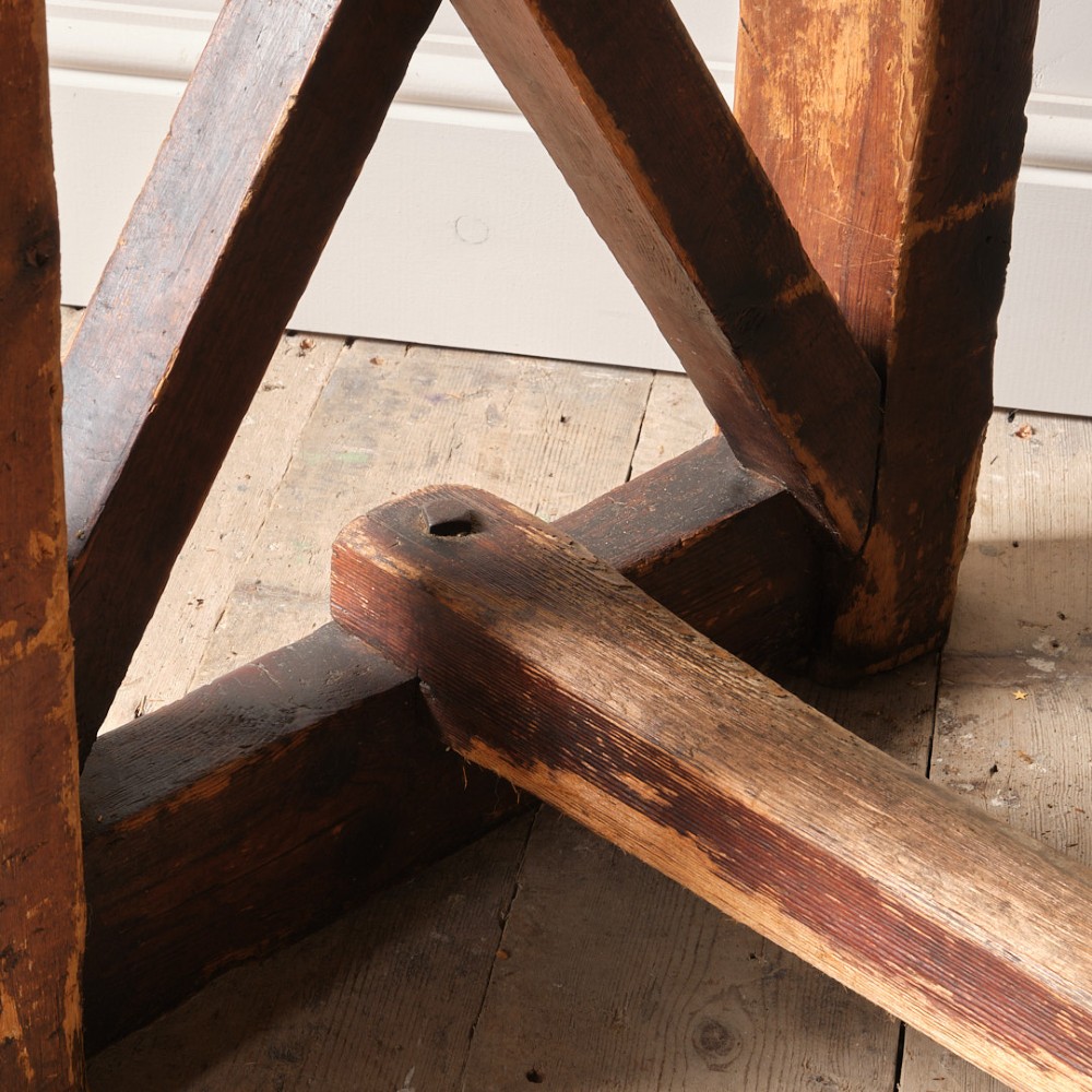 A long antique pine workbench table featuring a heavy plank top supported by a sturdy timber frame with X-frame cross bracing. View XII