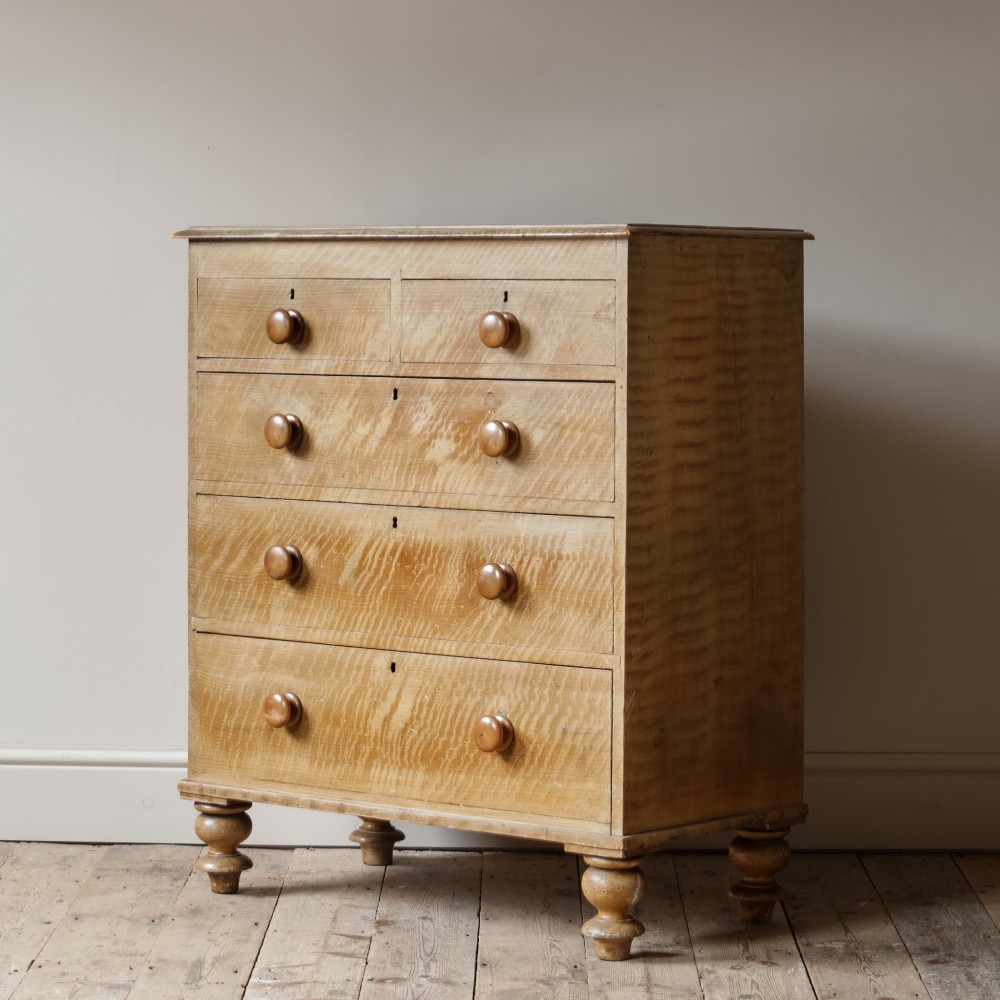 A mid-nineteenth-century pine chest of drawers featuring a faux-grain painted finish, turned wooden knobs, two short drawers over three long drawers, and turned feet. View II