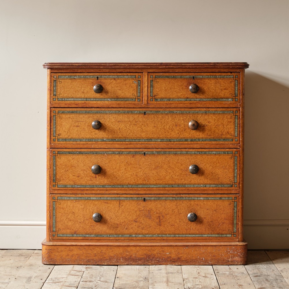 A 19th-century pine chest of drawers featuring an ochre painted finish with decorative green line borders, two short drawers over three long drawers, and turned wooden knobs.