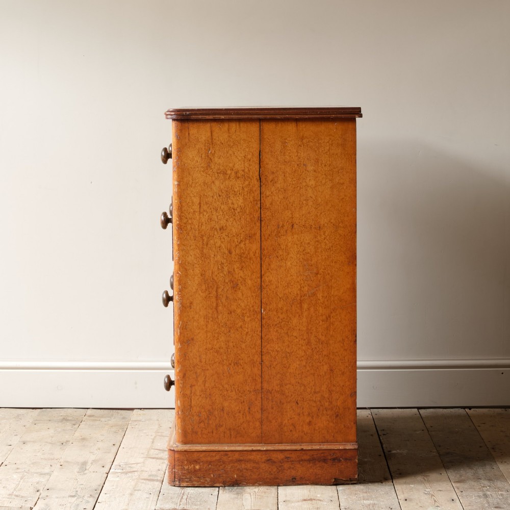 A 19th-century pine chest of drawers featuring an ochre painted finish with decorative green line borders, two short drawers over three long drawers, and turned wooden knobs. View IV