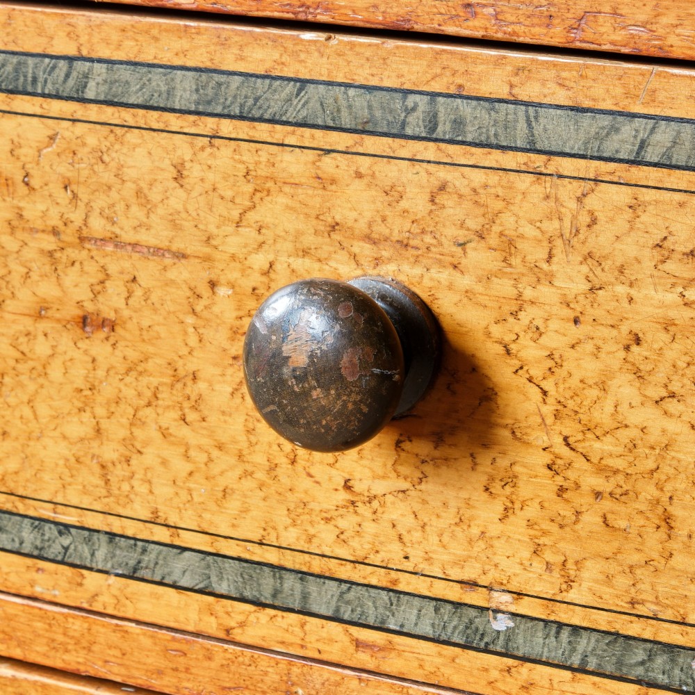 A 19th-century pine chest of drawers featuring an ochre painted finish with decorative green line borders, two short drawers over three long drawers, and turned wooden knobs. View X