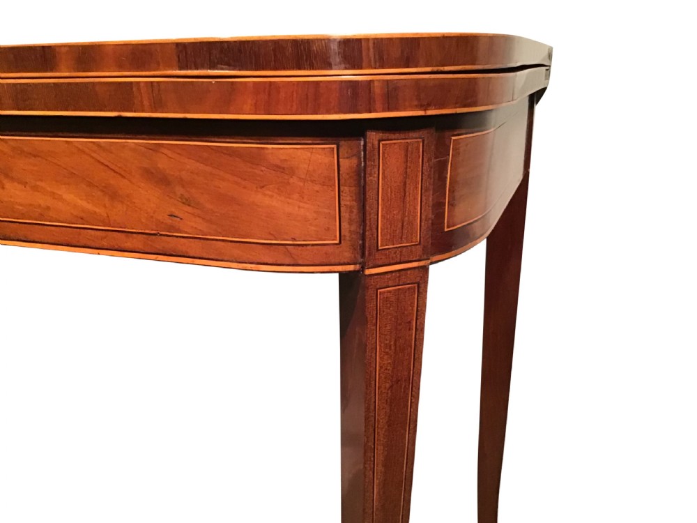 An antique mahogany fold-over tea table with crossbanded top inlay and slender curved legs set against a plain grey background. View II