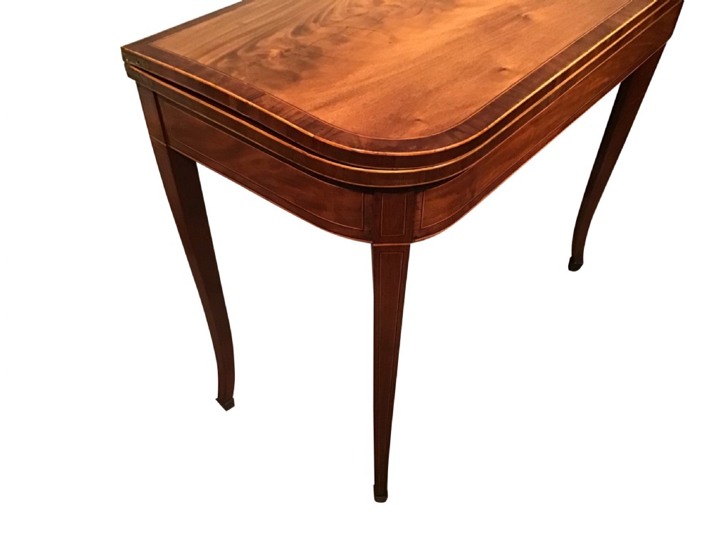 An antique mahogany fold-over tea table with crossbanded top inlay and slender curved legs set against a plain grey background. View IV