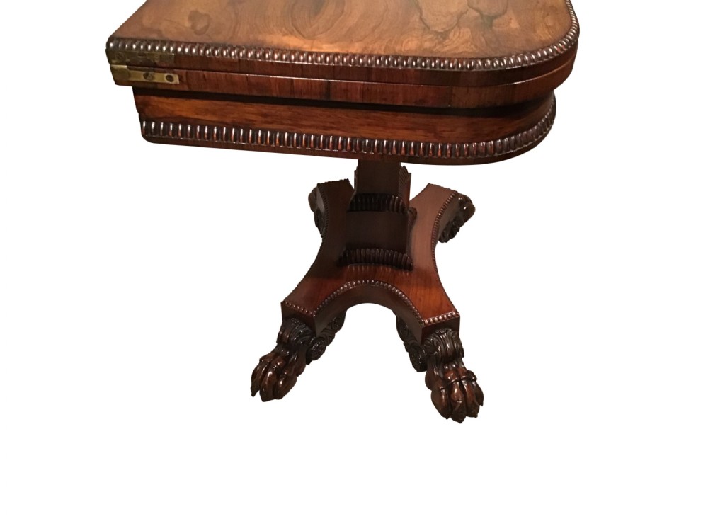 A William IV rosewood fold-over card table featuring a rectangular top with rounded corners, gadrooned edging, a central pedestal stem, and a carved quadform base resting on paw feet. View IV