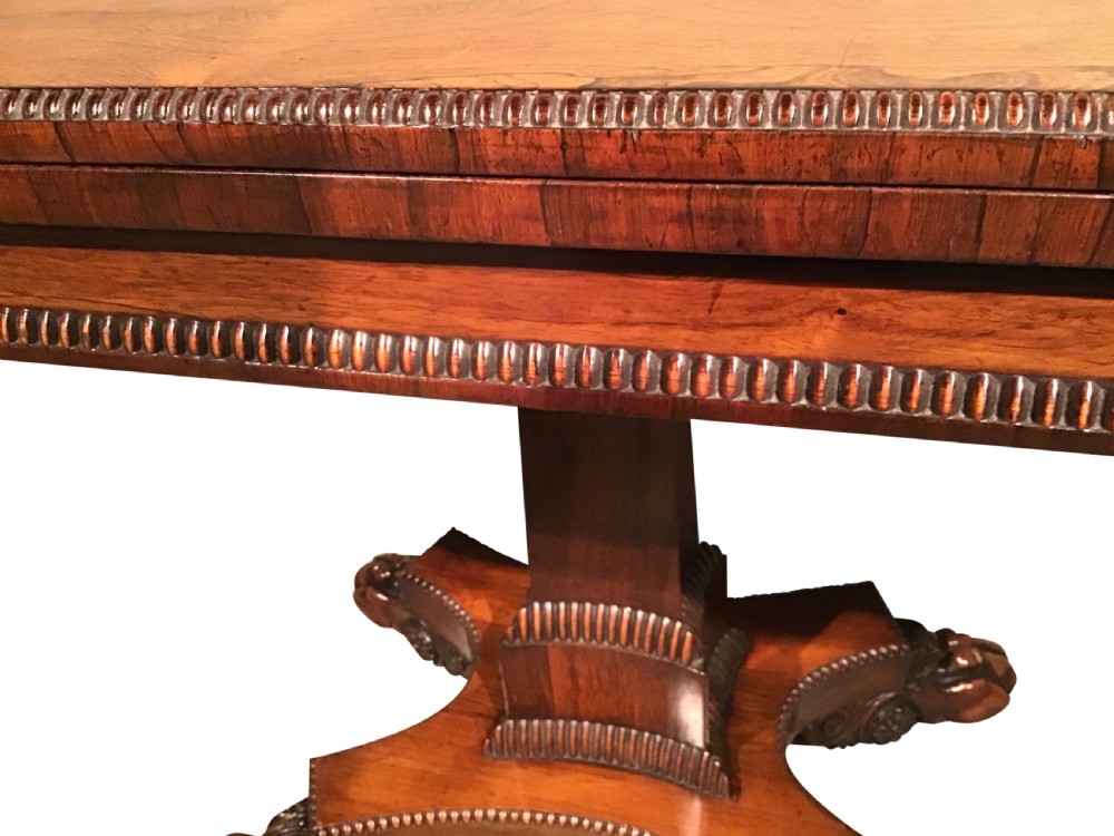 A William IV rosewood fold-over card table featuring a rectangular top with rounded corners, gadrooned edging, a central pedestal stem, and a carved quadform base resting on paw feet. View VI