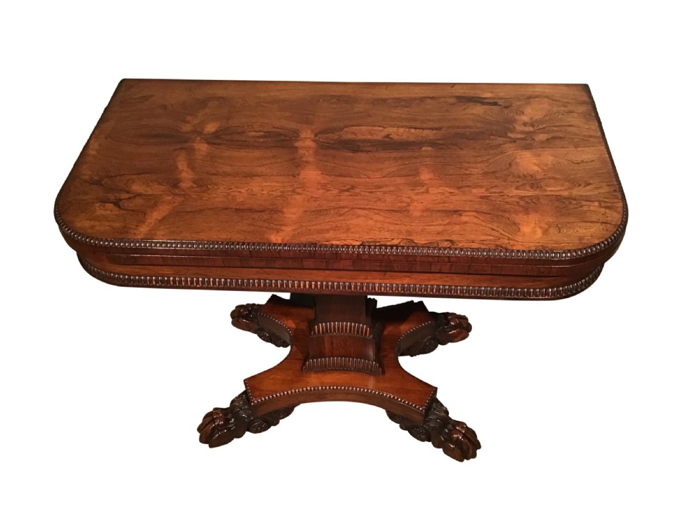 A William IV rosewood fold-over card table featuring a rectangular top with rounded corners, gadrooned edging, a central pedestal stem, and a carved quadform base resting on paw feet. View VIII