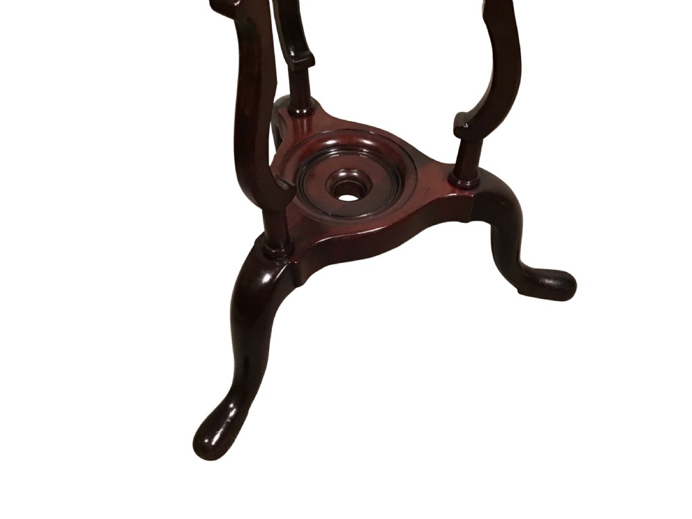 A dark mahogany Georgian wig stand featuring a circular top ring, a triangular drawer section with an urn finial, and a tripod base with cabriole legs. View III