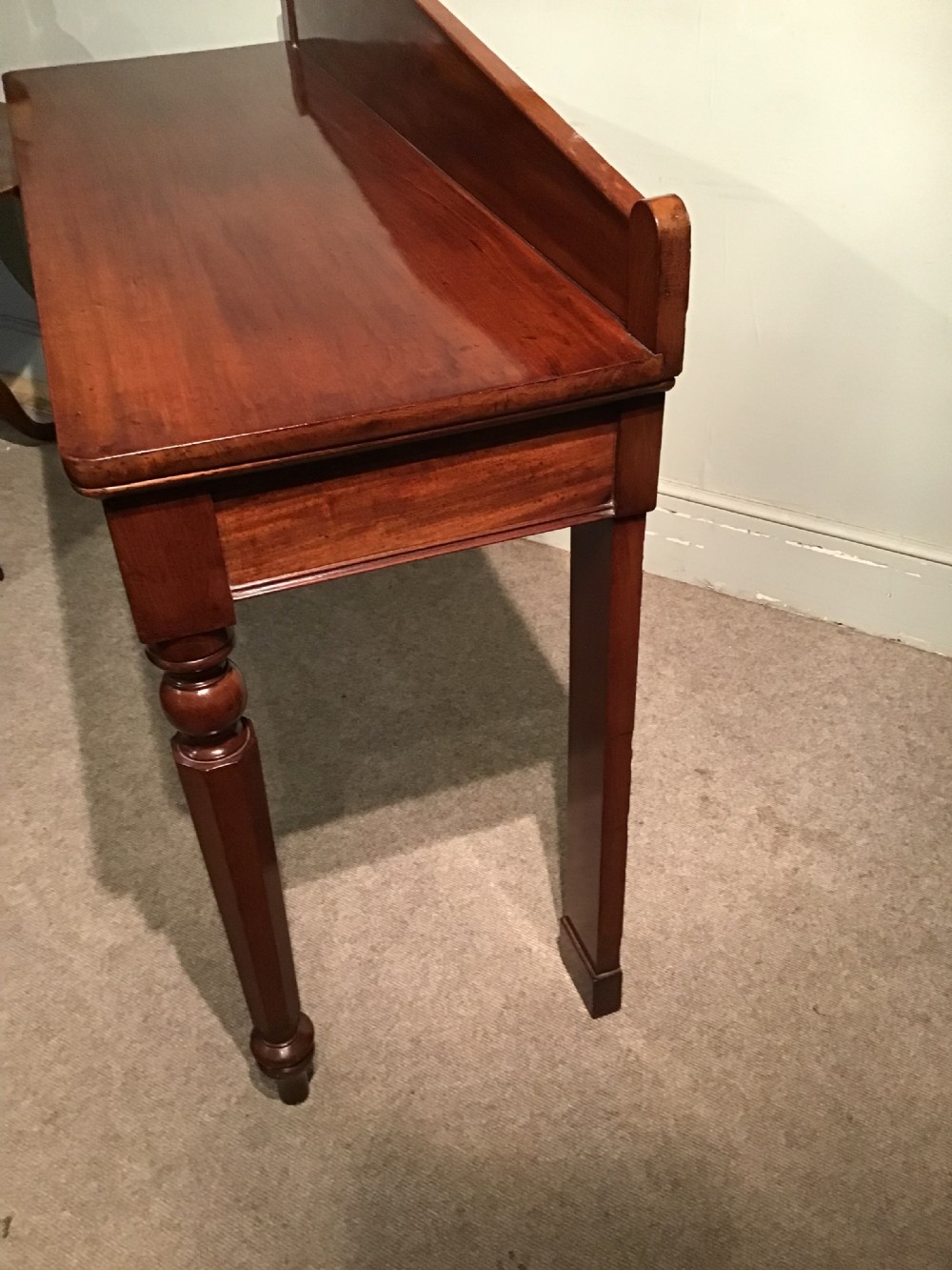 A mahogany serving table featuring a raised shaped backboard gallery, polished rectangular top, plain apron, and turned front legs. View IV