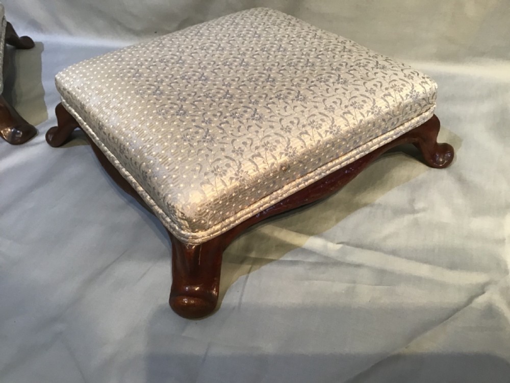 A pair of low antique footstools featuring dark carved mahogany cabriole legs and silver floral patterned upholstery. View III
