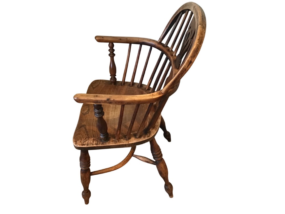An antique wooden Windsor armchair featuring a hoop back with a pierced splat, vertical spindles, curved armrests, and turned legs. View III