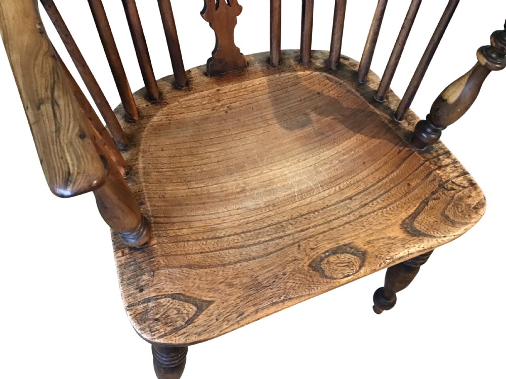 An antique wooden Windsor armchair featuring a hoop back with a pierced splat, vertical spindles, curved armrests, and turned legs. View IV