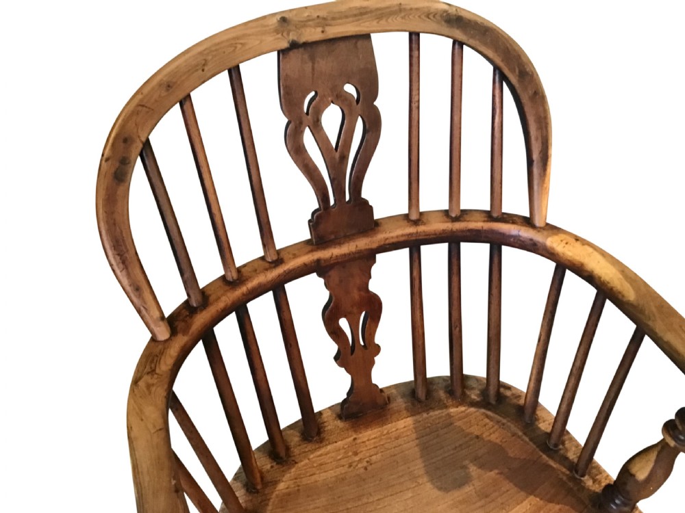 An antique wooden Windsor armchair featuring a hoop back with a pierced splat, vertical spindles, curved armrests, and turned legs. View V