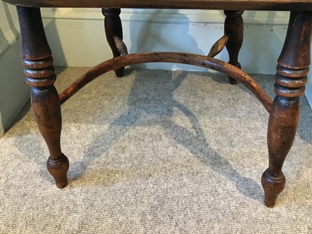 An antique wooden Windsor armchair featuring a hoop back with a pierced splat, vertical spindles, curved armrests, and turned legs. View VI