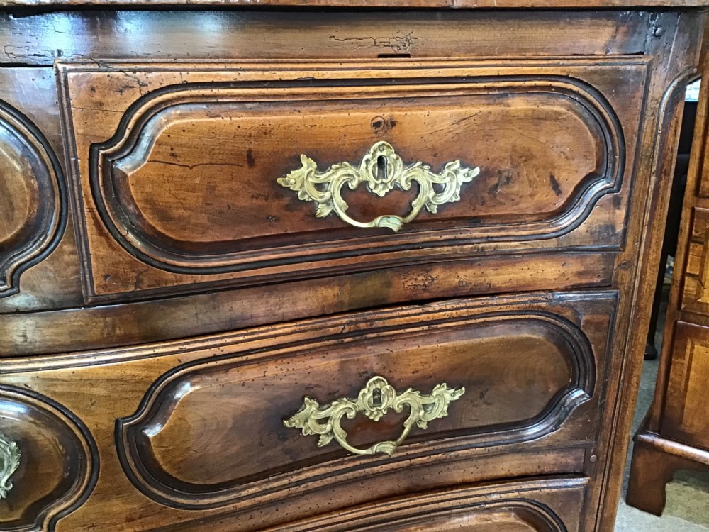 An antique French Louis XV style walnut commode featuring three contoured drawers with moulded panels and ornamental brass handles on cabriole legs. View VII