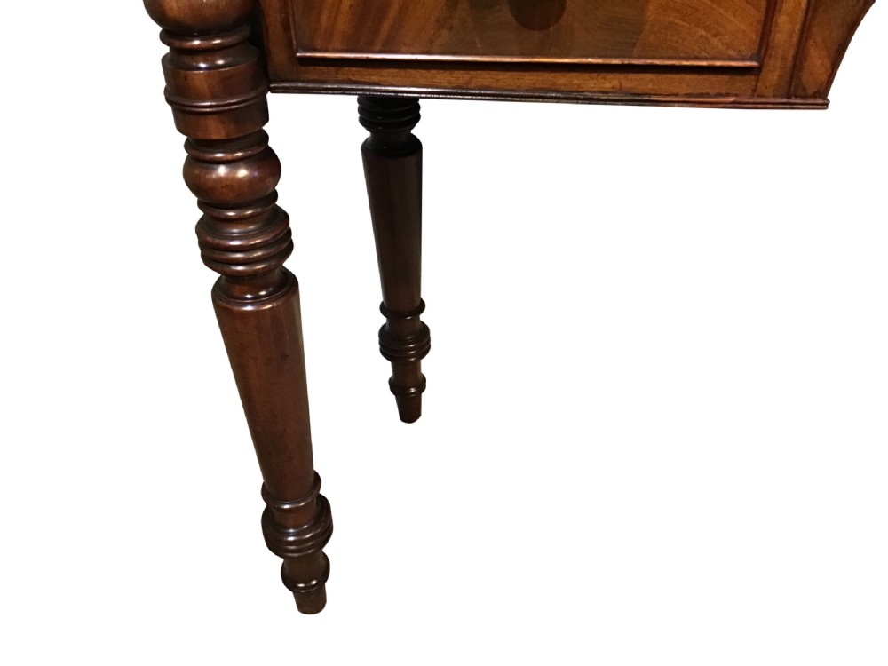 An antique mahogany hall table featuring a gallery back, five drawers with turned knobs, an arched kneehole centre, and four turned legs. View V