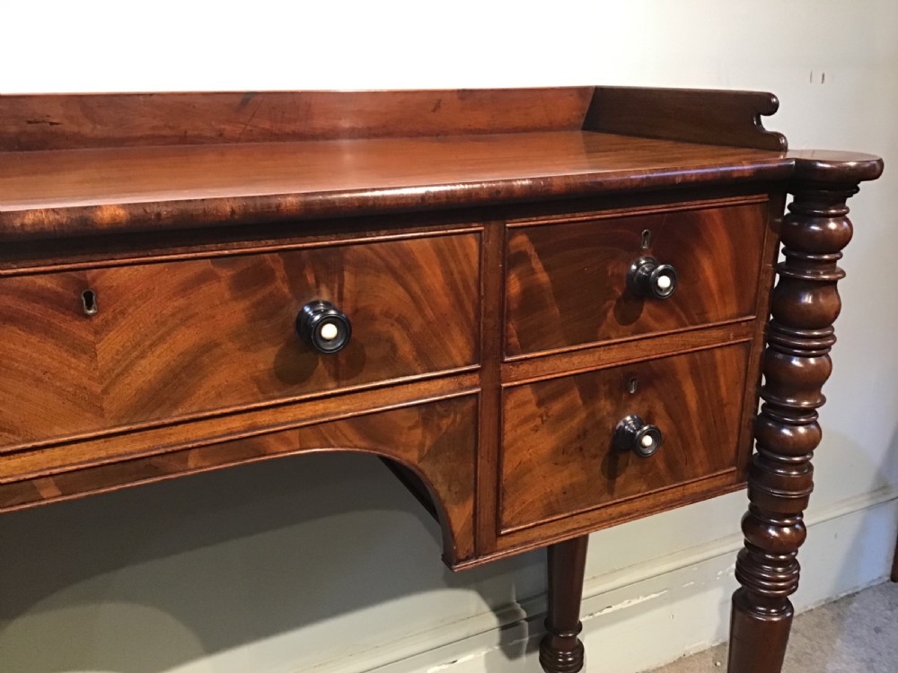 An antique mahogany hall table featuring a gallery back, five drawers with turned knobs, an arched kneehole centre, and four turned legs. View XII