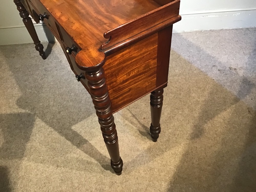 An antique mahogany hall table featuring a gallery back, five drawers with turned knobs, an arched kneehole centre, and four turned legs. View XVI
