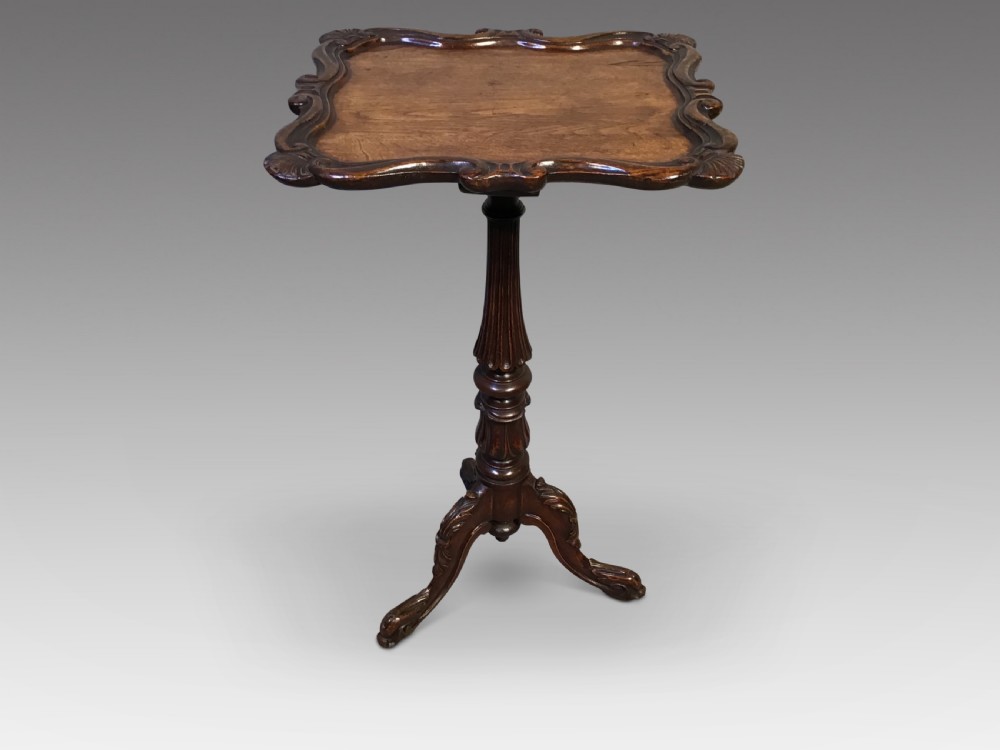 An antique dark oak wine table featuring a shaped piecrust top supported by a turned pedestal column and a carved tripod base.