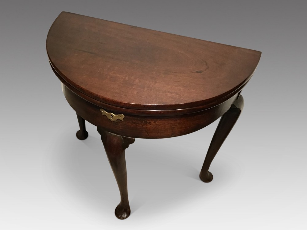 A dark mahogany demi-lune fold-over tea table featuring cabriole legs ending in pad feet and a central brass keyhole escutcheon. View II