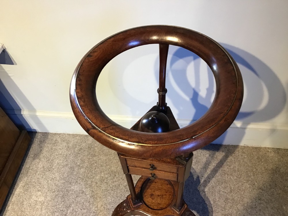 An antique Georgian mahogany tripod washstand featuring an upper basin ring, a middle triangular drawer section with an urn finial, and cabriole legs. View II