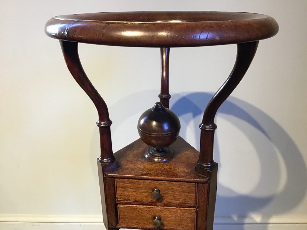 An antique Georgian mahogany tripod washstand featuring an upper basin ring, a middle triangular drawer section with an urn finial, and cabriole legs. View III