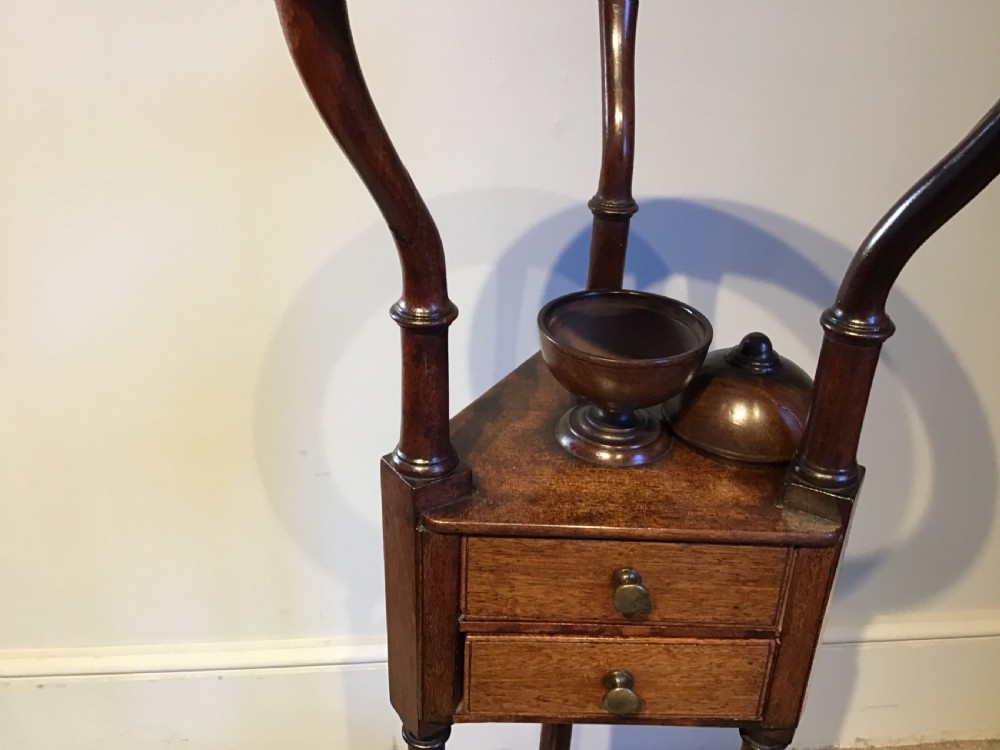 An antique Georgian mahogany tripod washstand featuring an upper basin ring, a middle triangular drawer section with an urn finial, and cabriole legs. View IV