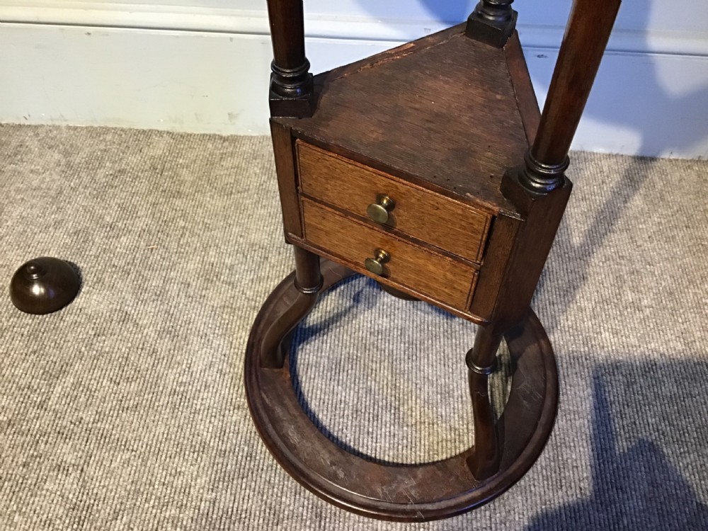An antique Georgian mahogany tripod washstand featuring an upper basin ring, a middle triangular drawer section with an urn finial, and cabriole legs. View IX