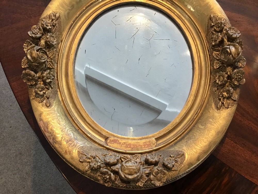 A pair of oval giltwood mirrors featuring detailed floral moulding and engraved detailing along the gilded frames. View III