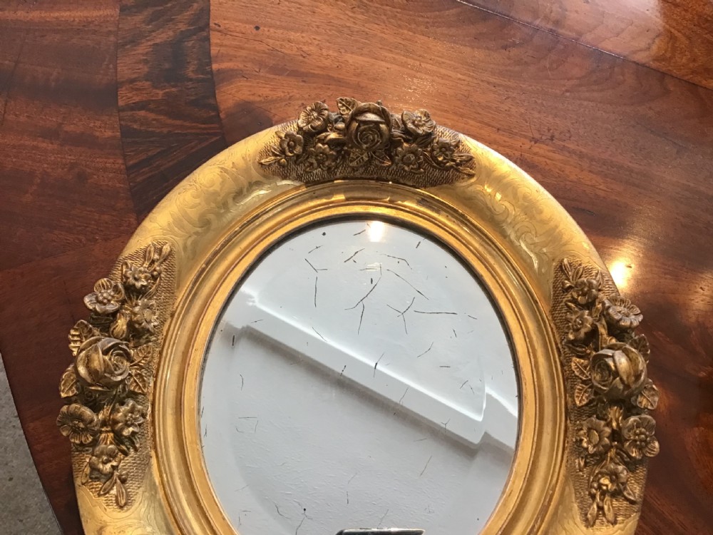 A pair of oval giltwood mirrors featuring detailed floral moulding and engraved detailing along the gilded frames. View IV